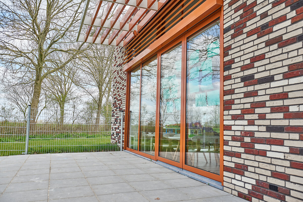Oranje aluminium kozijnen Mienskipskaolle Sibrandabuorren